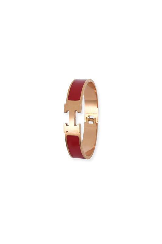 Gold bracelet with red band on a white background